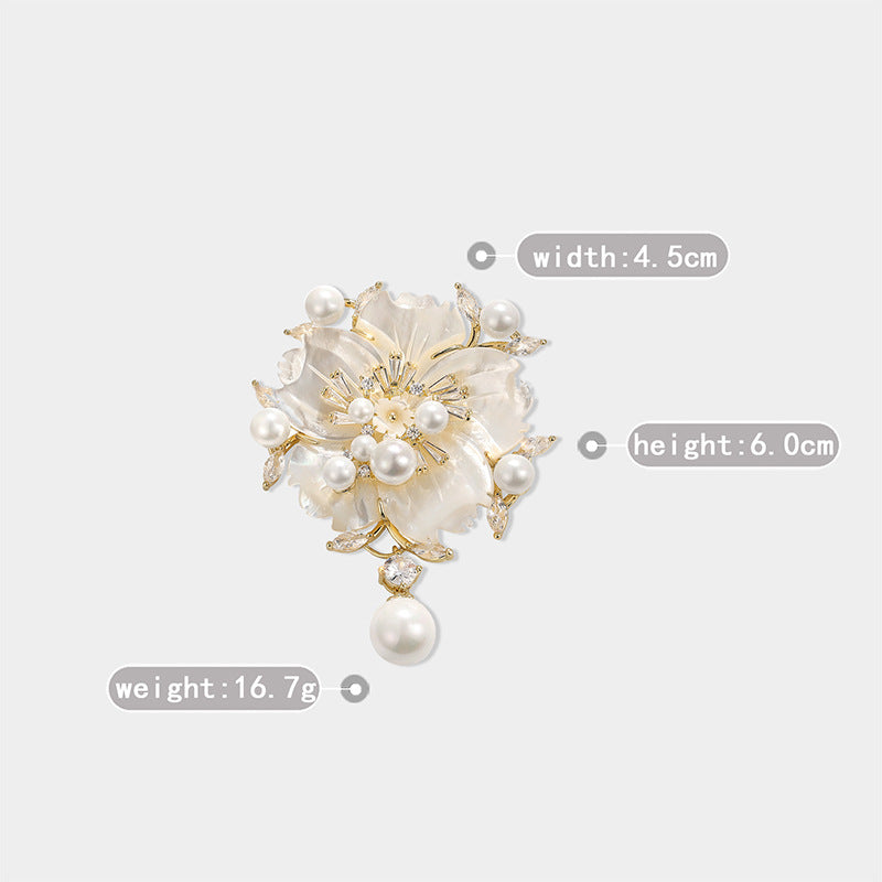 A gold-tone floral brooch with white faux pearls and a white mother-of-pearl center, shown on a light gray background with overlaid dimension labels for width, height, and weight.