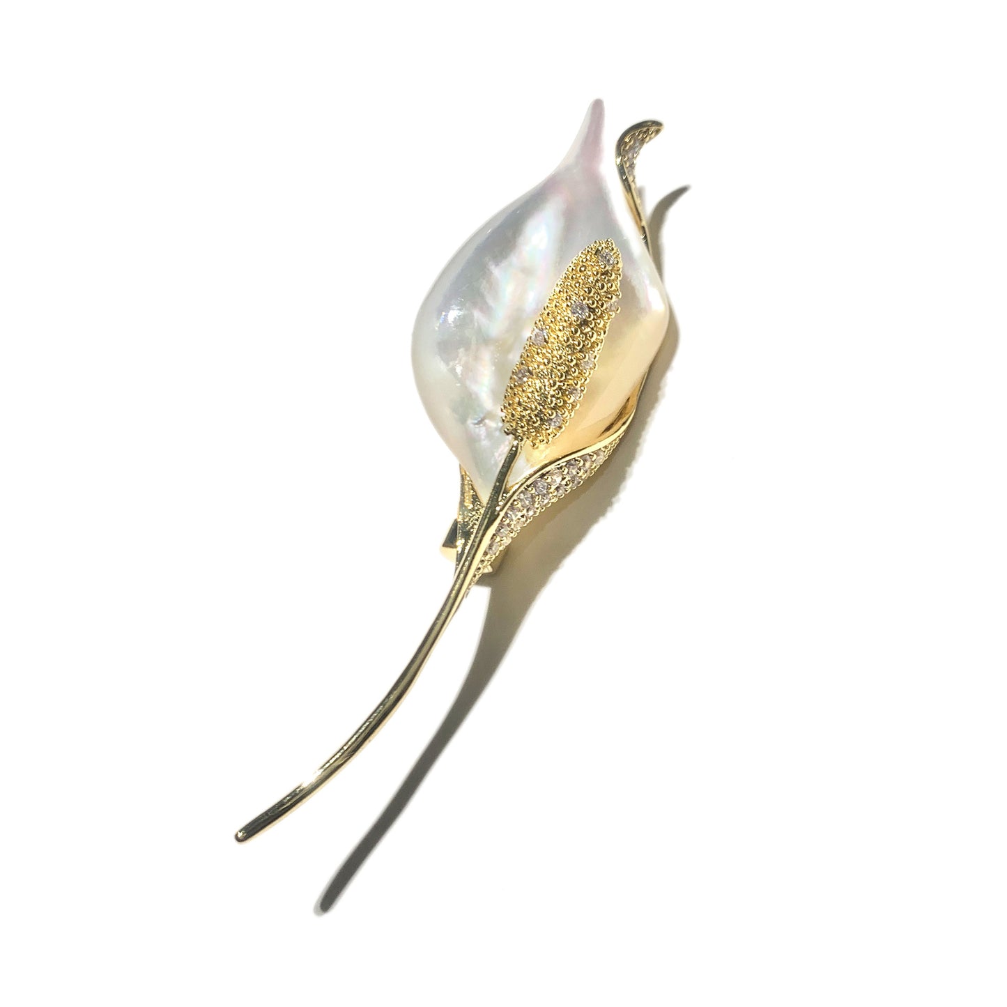 A calla lily flower brooch featuring a white mother-of-pearl center, a textured gold stamen, and gold leaves accented with small clear crystals, set against a plain white background with a soft shadow.