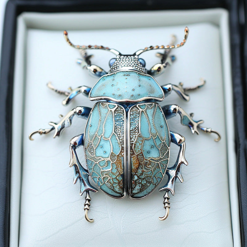 Decorative beetle-shaped object with turquoise and silver design on a white background