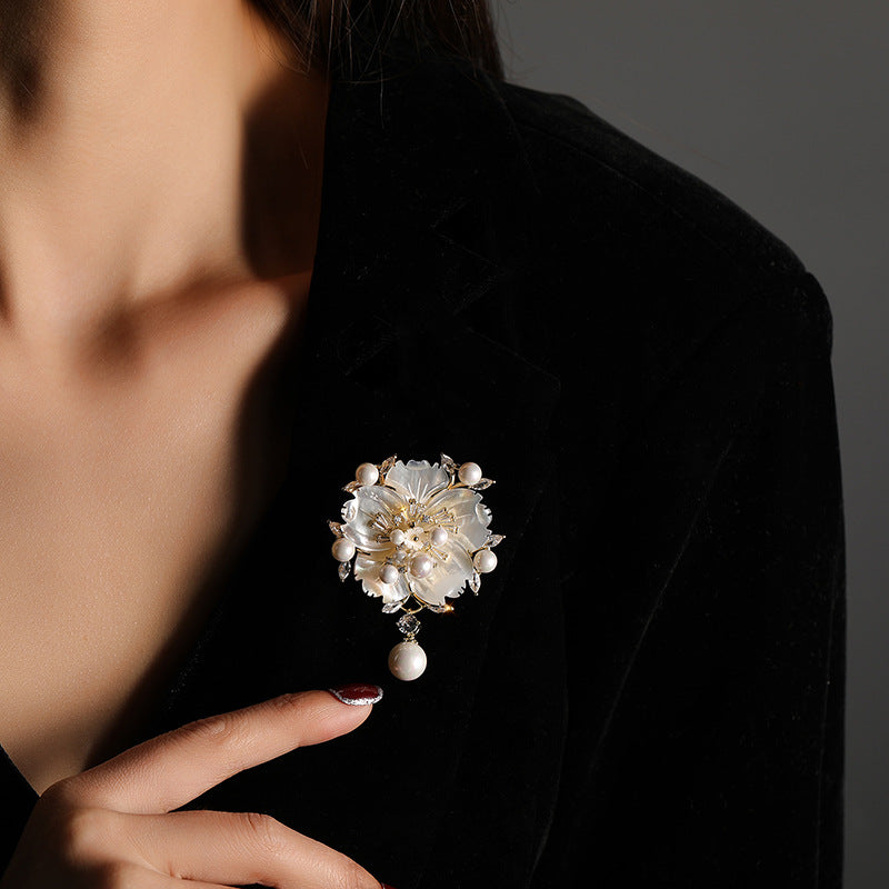 Close-up of a decorative brooch on a dark jacket with a blurred face.