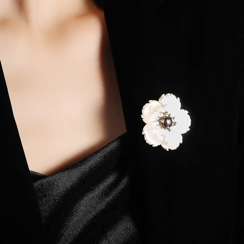 White flower-shaped brooch on a black background