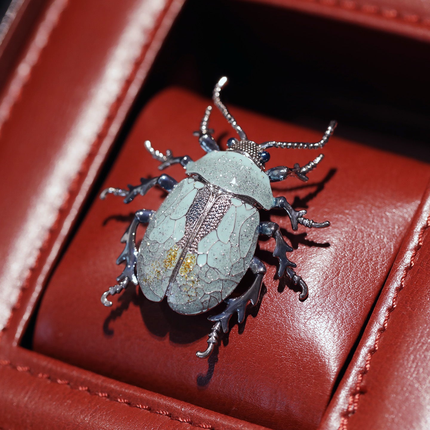 Decorative beetle-shaped object on a red leather surface