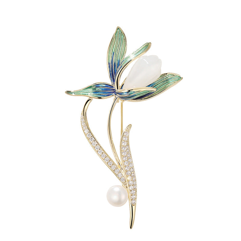 A gold-tone floral brooch featuring a butterfly with blue and green enamel wings, a pearl at the center, and a pearl and crystal-encrusted stem, set against a clean white background with soft shadows.