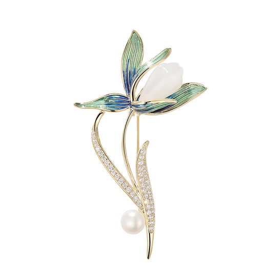 A gold-tone floral brooch featuring a butterfly with blue and green enamel wings, a pearl at the center, and a pearl and crystal-encrusted stem, set against a clean white background with soft shadows.